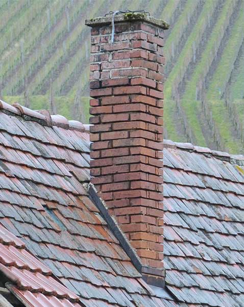 Traditions Chimney Sweeps Leaky Chimneys. Leaky Chimneys - tall chimney with spalling with fields in the background.