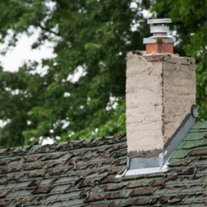 a damaged concrete chimney surrounding by damaged shingles and roofing